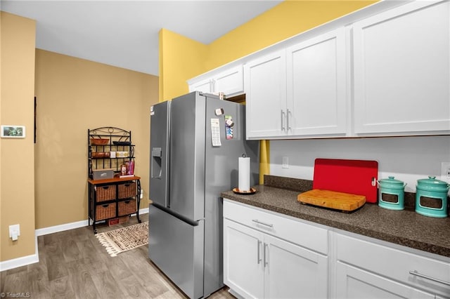 1009 Cannonade Dr, Whitsett, NC 27377 - kitchen with stainless steel refrigerator with ice dispenser, light wood finished floors, dark countertops, white cabinetry, and baseboards