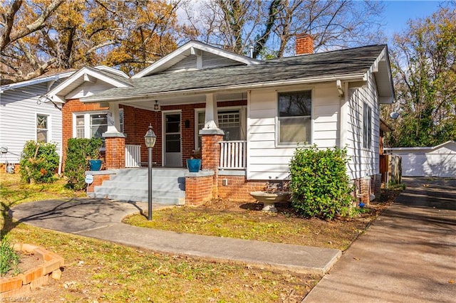 bungalow-style home featuring an outbuilding, covered porch, and a garage