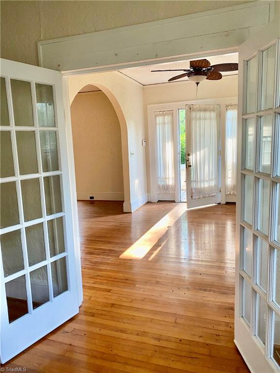 entryway with arched walkways, light wood-type flooring, a ceiling fan, and baseboards