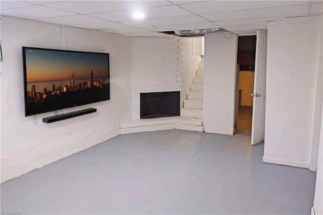 unfurnished living room featuring concrete flooring, a drop ceiling, and a fireplace