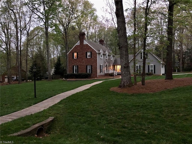 view of front of property with brick siding, a chimney, and a front yard