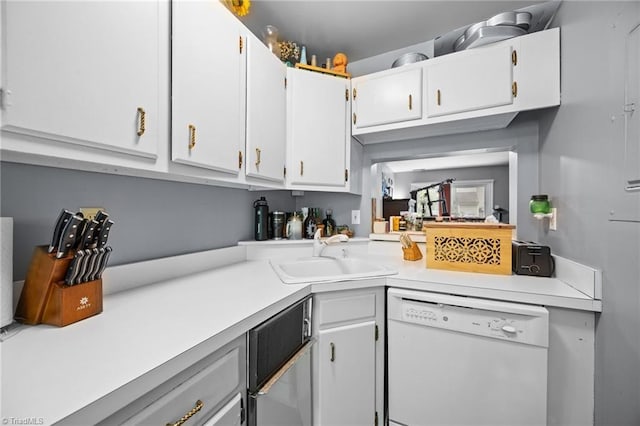 217 Village Ln Unit G, Greensboro, NC 27409 - kitchen featuring dishwasher, a sink, light countertops, and white cabinetry