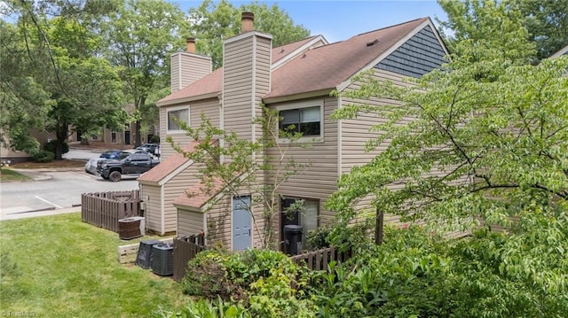 217 Village Ln Unit G, Greensboro, NC 27409 - rear view of property featuring a chimney, central AC, and a yard