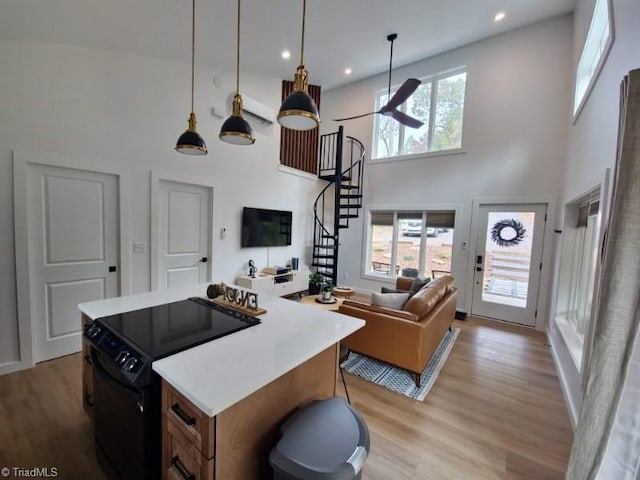 kitchen with black range with electric cooktop, a healthy amount of sunlight, a towering ceiling, and decorative light fixtures