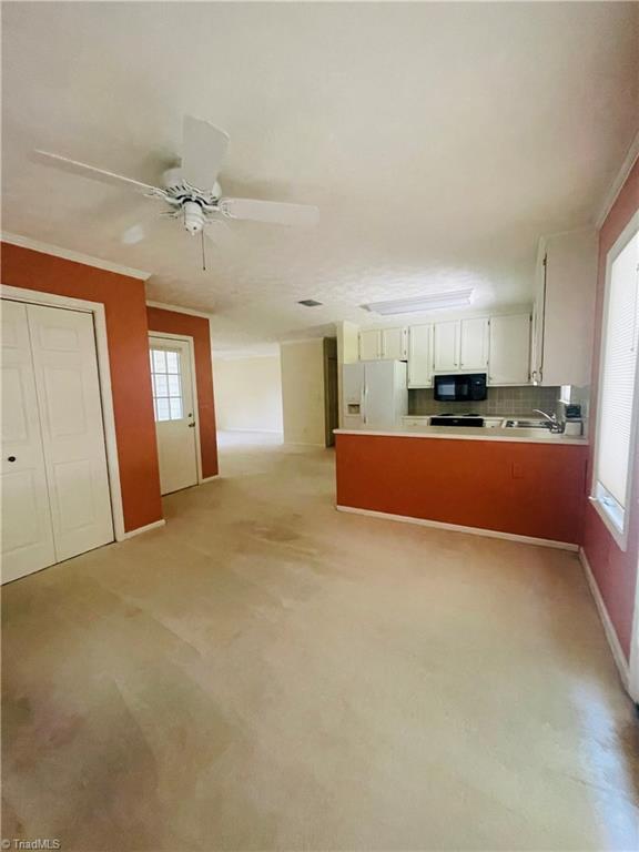 kitchen with white refrigerator with ice dispenser, a wealth of natural light, white cabinets, and decorative backsplash