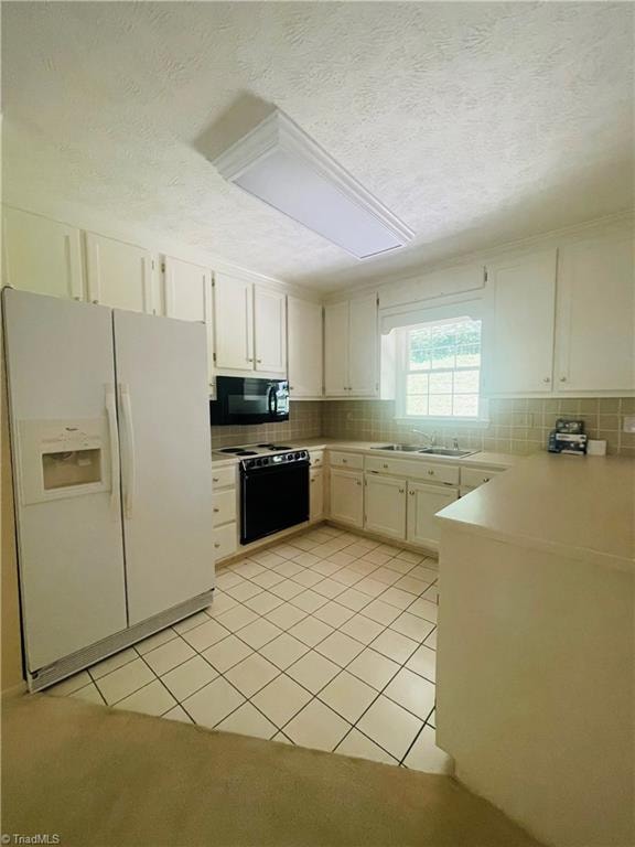 kitchen featuring tasteful backsplash, a textured ceiling, light tile patterned floors, black appliances, and sink