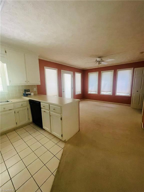 kitchen featuring a wealth of natural light, light colored carpet, dishwasher, and kitchen peninsula