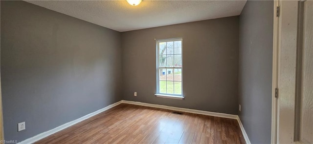 empty room with hardwood / wood-style floors and a textured ceiling