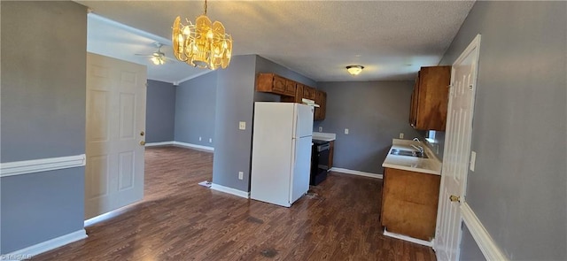 kitchen featuring dark wood-type flooring, ceiling fan with notable chandelier, white refrigerator, sink, and a textured ceiling