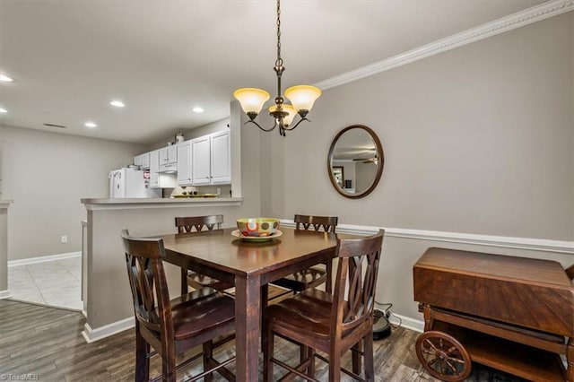 dining room with baseboards, ornamental molding, wood finished floors, a notable chandelier, and recessed lighting