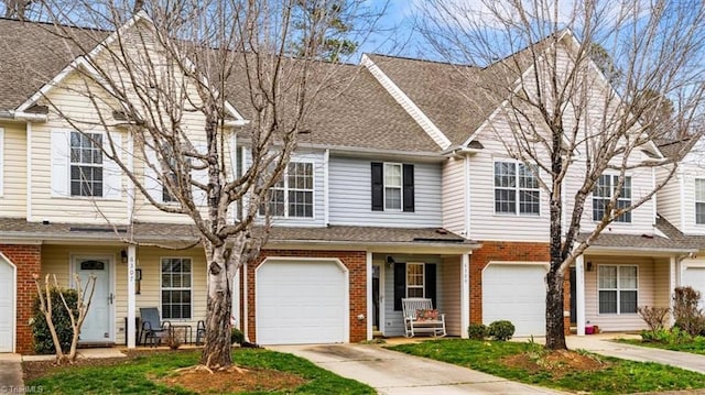 view of property featuring driveway, brick siding, an attached garage, and a shingled roof