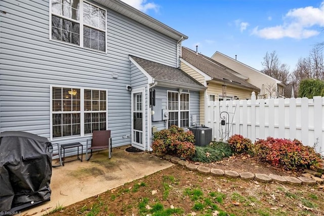 back of property featuring a patio, a shingled roof, cooling unit, and fence