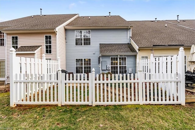 back of house with a yard, roof with shingles, and fence