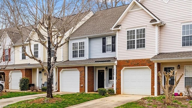 view of property featuring a garage, concrete driveway, brick siding, and a shingled roof