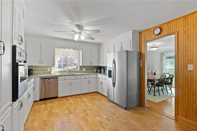 kitchen featuring white cabinets, sink, ceiling fan, light wood-type flooring, and appliances with stainless steel finishes