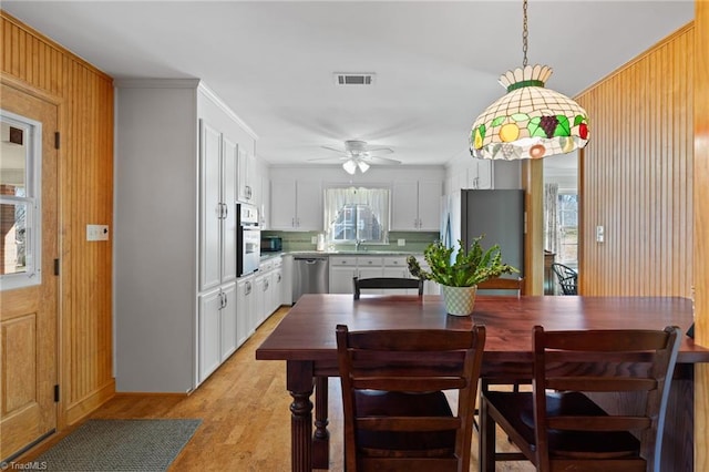 dining area featuring ceiling fan, sink, light hardwood / wood-style floors, and ornamental molding