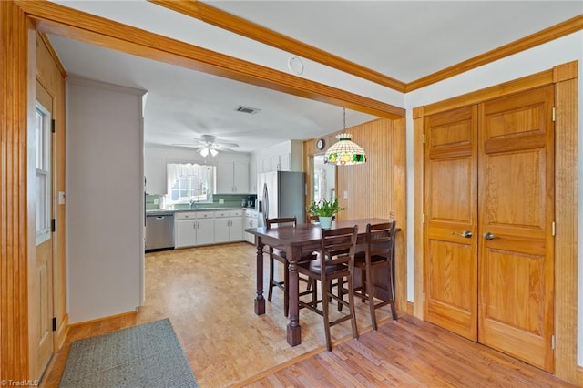 dining room with light hardwood / wood-style floors, ceiling fan, and crown molding