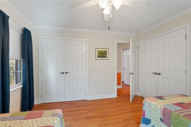 bedroom with multiple closets, light hardwood / wood-style flooring, ceiling fan, and crown molding