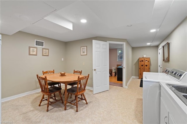 dining space with washer and dryer and light colored carpet