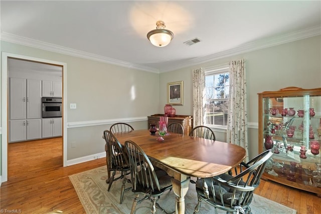 dining room with light hardwood / wood-style flooring and ornamental molding