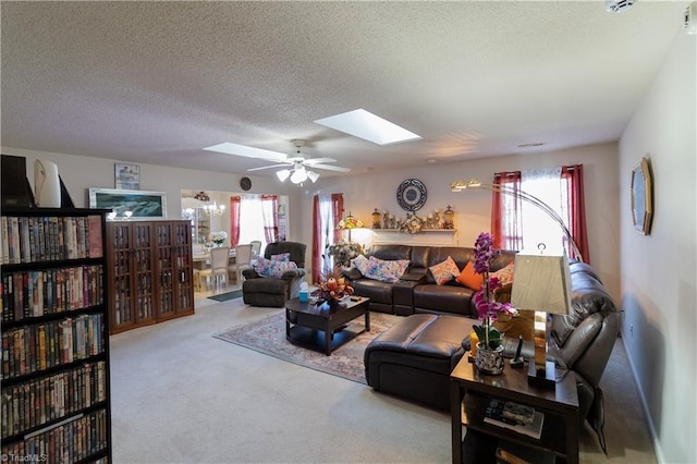 living room with ceiling fan, a skylight, carpet flooring, and a textured ceiling