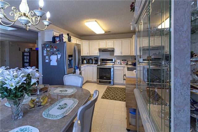 kitchen with pendant lighting, appliances with stainless steel finishes, white cabinetry, a textured ceiling, and a chandelier