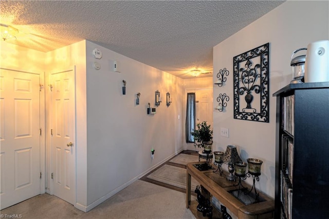 hall with light carpet and a textured ceiling