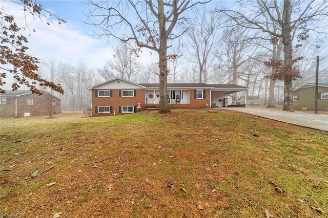 view of front of home with brick siding, an attached carport, concrete driveway, and a front yard