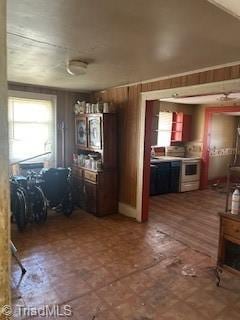 kitchen with a healthy amount of sunlight, white electric range, and wooden walls