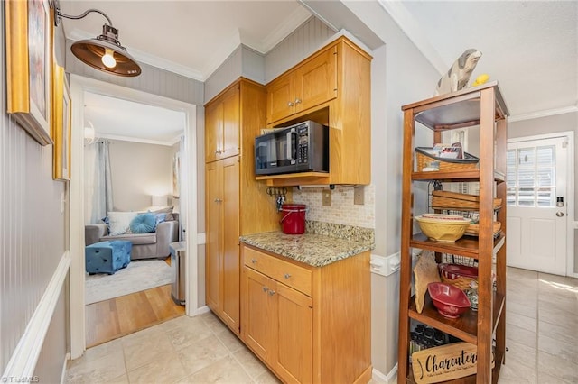 kitchen featuring black microwave, ornamental molding, light tile patterned flooring, and tasteful backsplash