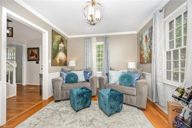 sitting room with baseboards, ornamental molding, wood finished floors, and a notable chandelier