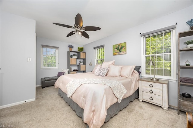 bedroom featuring light colored carpet, a ceiling fan, baseboards, and multiple windows