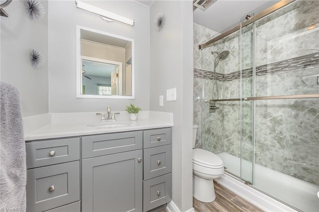 full bathroom with vanity, toilet, wood finished floors, and a stall shower