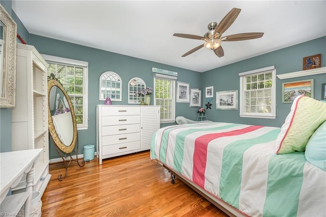 bedroom with ceiling fan, multiple windows, and light wood-style floors
