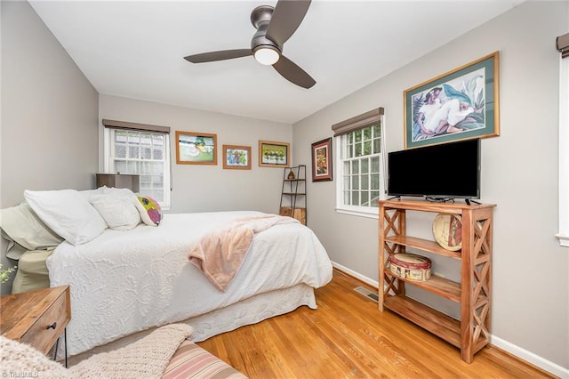 bedroom with baseboards, wood finished floors, and multiple windows
