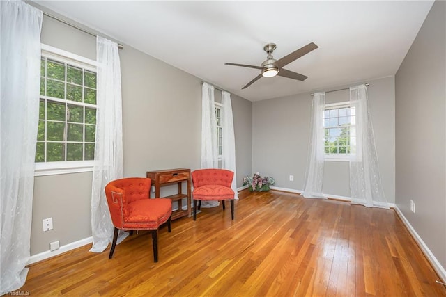 living area with baseboards, ceiling fan, and hardwood / wood-style flooring