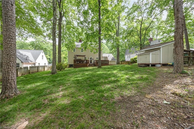 view of yard featuring fence, an outdoor structure, a deck, and a shed