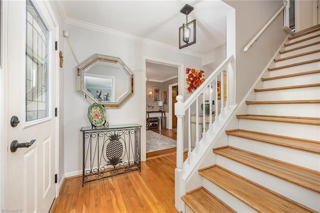 stairway featuring baseboards, ornamental molding, and wood finished floors