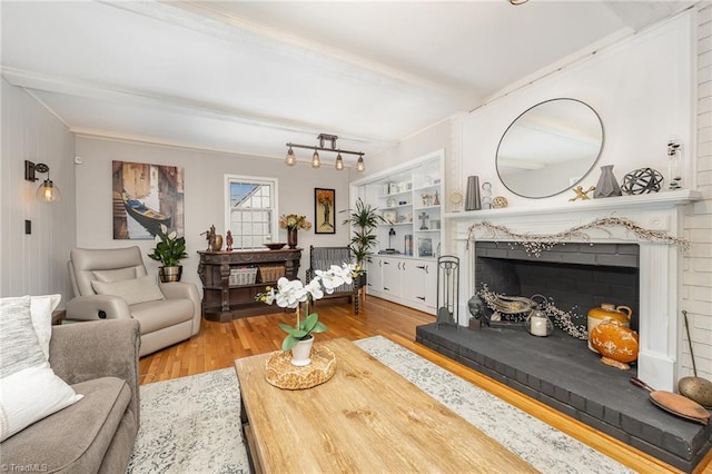 living room featuring crown molding, a brick fireplace, and wood finished floors