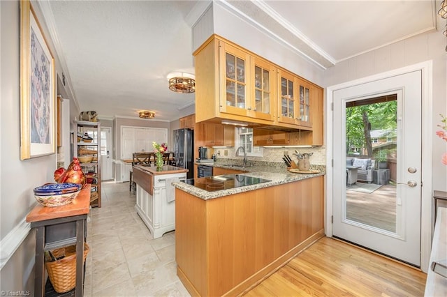 kitchen featuring crown molding, freestanding refrigerator, a sink, and glass insert cabinets