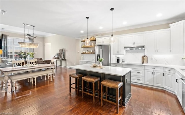 kitchen with a center island, dark wood-type flooring, stainless steel appliances, decorative light fixtures, and white cabinets