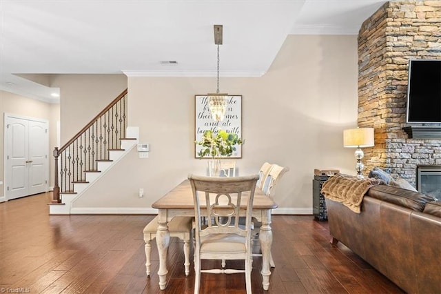 dining space featuring dark hardwood / wood-style floors, a stone fireplace, and crown molding