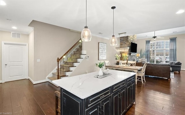 kitchen with decorative light fixtures, ceiling fan, a kitchen island, and dark hardwood / wood-style floors