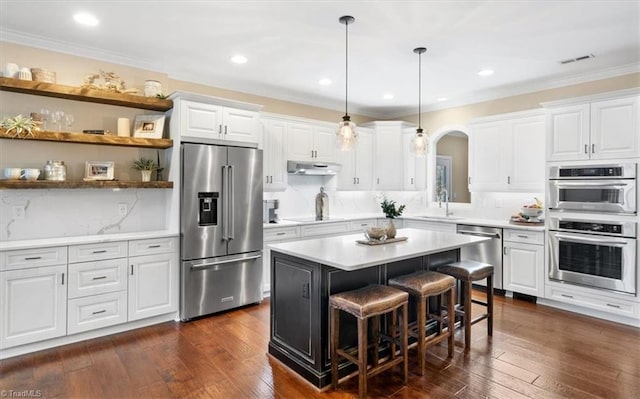 kitchen featuring a breakfast bar, a center island, dark hardwood / wood-style flooring, white cabinetry, and stainless steel appliances