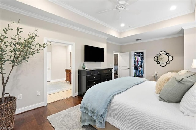 bedroom featuring ornamental molding, ceiling fan, a spacious closet, dark hardwood / wood-style floors, and a closet