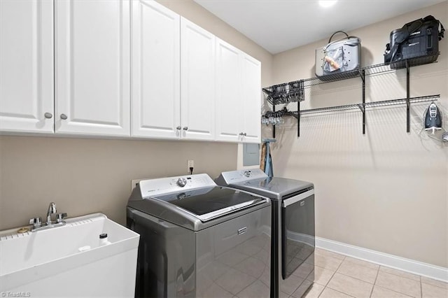 clothes washing area with cabinets, light tile patterned floors, sink, and washing machine and clothes dryer