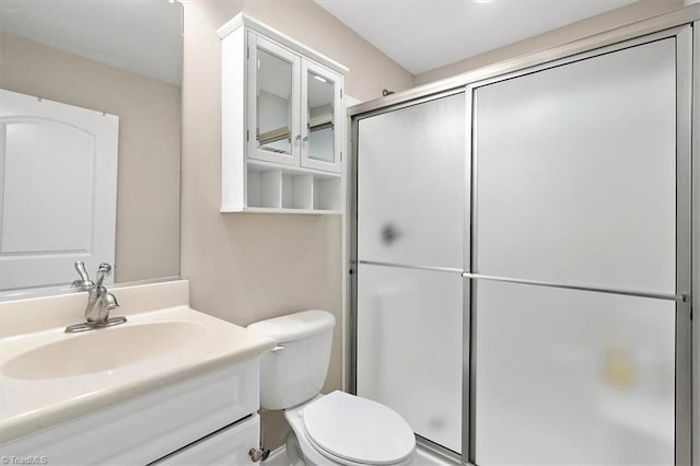 bathroom featuring vanity, toilet, and a shower with door