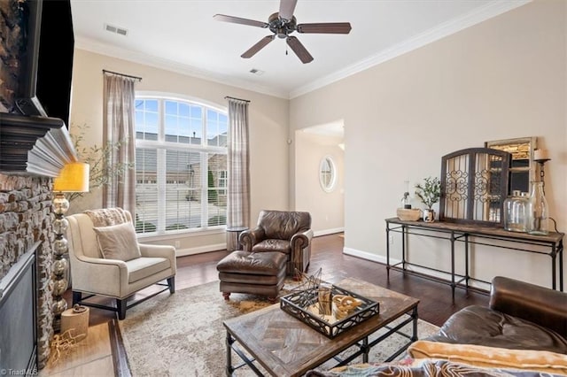 living room with hardwood / wood-style flooring, ceiling fan, ornamental molding, and a fireplace