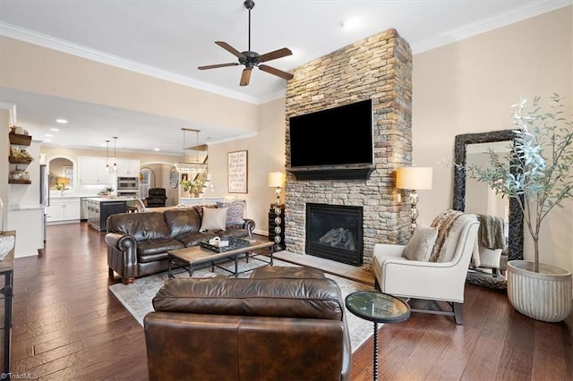 living room with ceiling fan, a fireplace, dark hardwood / wood-style floors, and ornamental molding