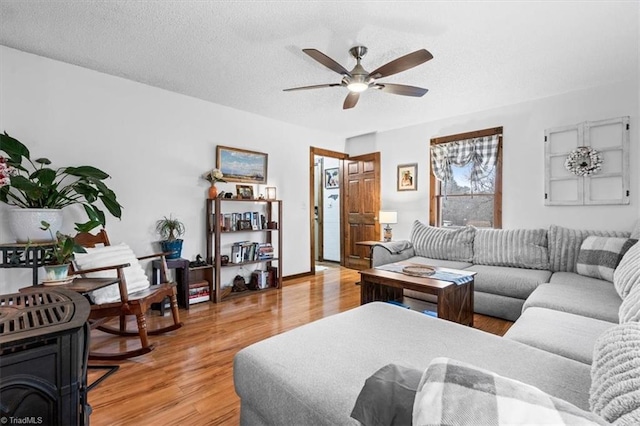 living room featuring ceiling fan, a textured ceiling, and light hardwood / wood-style flooring